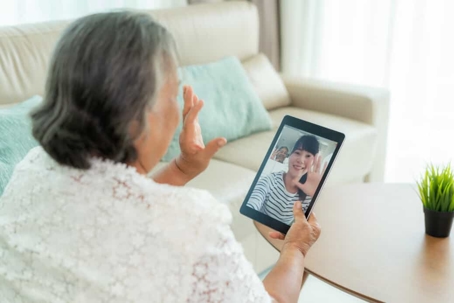 Senior woman waves to her daughter via video chat