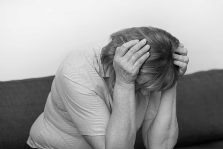 Senior woman holds her head in her hands in an upset condition