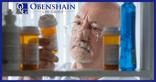 Older male doctor with white facial hair and glasses peers at a yellow prescription bottle