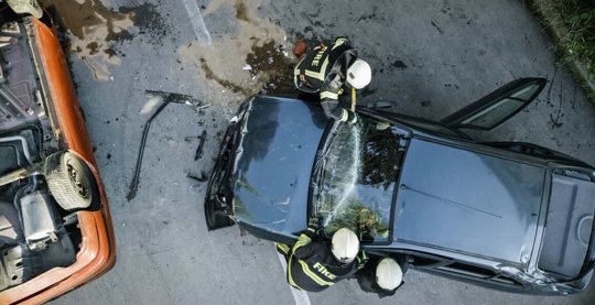 Aerial view of firefighters spraying down a car that's just been in an accident