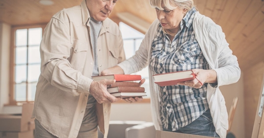 two older people packing boxes