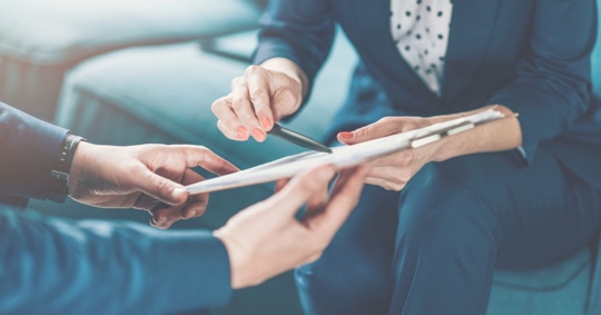 person handing someone a document to sign