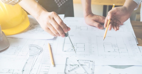 two people drawing on blueprints
