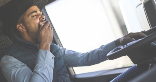 a truck driver yawning behind the wheel