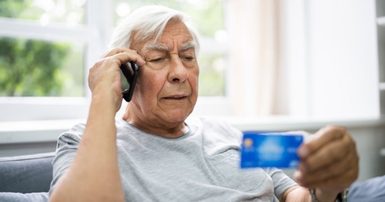 old man on phone looking at his credit card